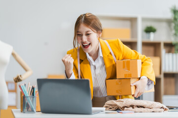 A young Asian businesswoman efficiently manages SMEs, utilizing her desk, tablet, laptop to handle...