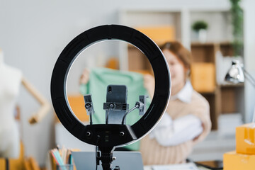 A young Asian businesswoman efficiently manages SMEs, utilizing her desk, tablet, laptop to handle...