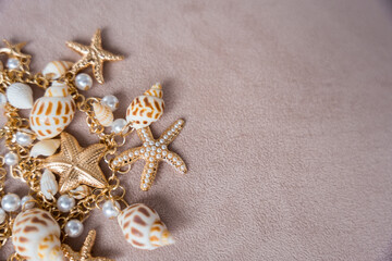 Gold necklace in a nautical style against a background of black marble: starfish, pearls and shells.