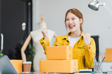 A young Asian businesswoman efficiently manages SMEs, utilizing her desk, tablet, laptop to handle...