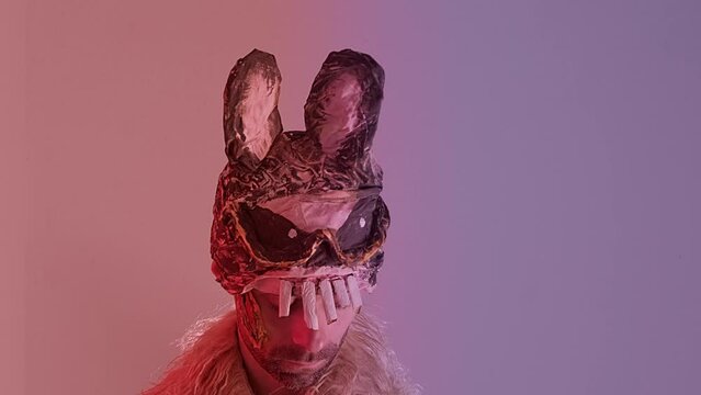 creepy man, young monster guy in cringe in scary bunny mask, juggling pumpkin, concept of Halloween party, theme of fear and horror associated with mask and facial expression, Festive Costumes