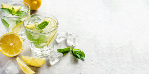 Two glasses of lemonade adorned with ice, lemon slices, and fresh mint leaves, evoking a refreshing summer vibe. Highlighting cooling drinks and seasonal enjoyment.