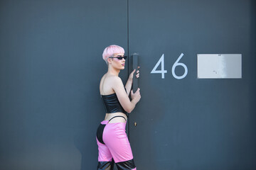 Attractive young gay man, heavily makeup, with pink hair, sunglasses, leather top and pants, posing...