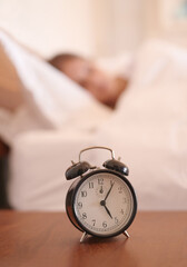 Sleeping, woman and closeup of alarm clock in bedroom with time for wake up, morning and snooze for...