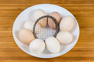 Boiled chicken eggs and old simple egg slicer in bowl