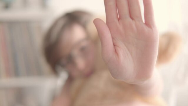 child with toy teddy bear, 11-year-old boy with defensive hand stop gesture, early diagnosis and intervention, support for people with autism, protective stance, domestic violence