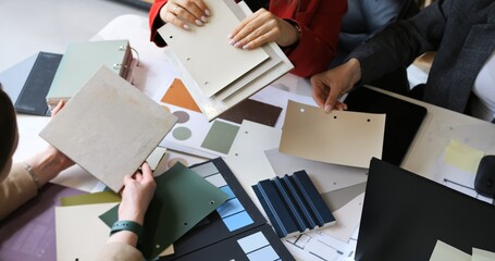 Fashion designers choosing fabric swatches in creative meeting. Professionals discuss textile...