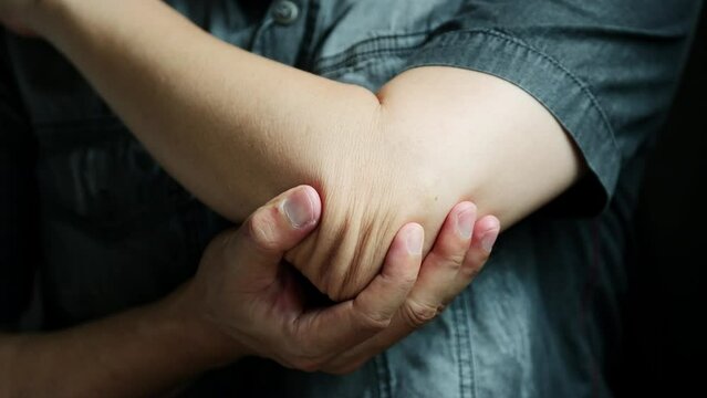 Man has pain in his elbow and tendon muscles and he relieves the pain with a massage. Health and healing concept
