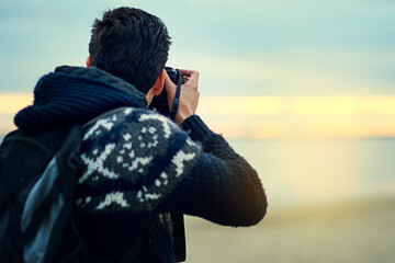 Beach, man and camera photography at sunset on holiday, travel or summer vacation in Spain. Dslr...