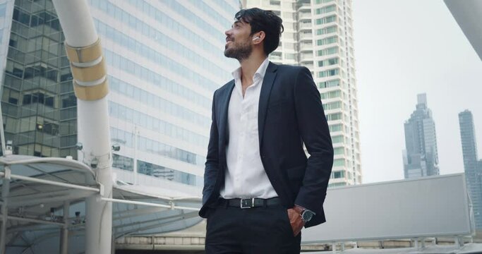 Successful negotiations completed, businessman in formal suit satisfaction. Wide smile and victorious gesture indicate successful. City financial district in background highlights successful deal.