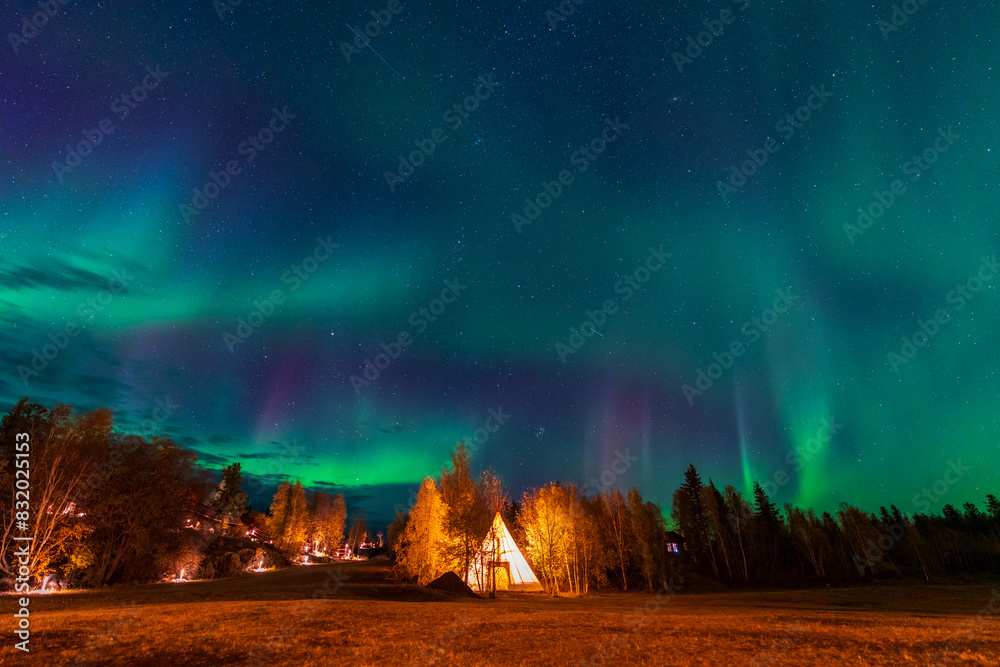Wall mural amazing northern lights dancing over the light up tipi or tepees at aurora village in yellowknife, n