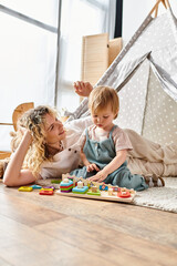Naklejka premium Mother and toddler happily play with Montessori toys on the floor.
