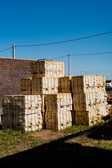 In a vast field, a stack of wooden crates is meticulously arranged, forming a structured heap. Each crate is placed carefully on top of the other, creating a precise and organized pile