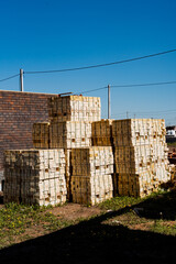 In a vast field, a stack of wooden crates is meticulously arranged, forming a structured heap. Each...