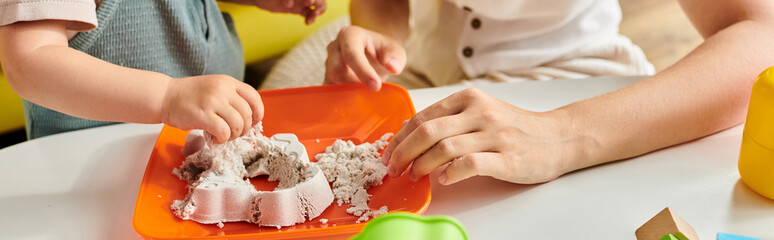 A child with mother is playfully experimenting with a plate using Montessori principles.