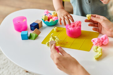 A child is engaged in molding colorful play dough on a table, exploring creativity with the...