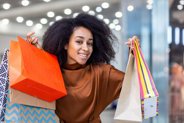 Happy young woman carrying multiple shopping bags in a mall. Enjoying a successful shopping day...