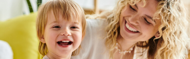 A curly mother and her toddler daughter share a moment of joy and laughter while engaging in...