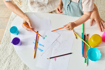 toddler and mom sit at a table drawing with colorful pencils and crayons.