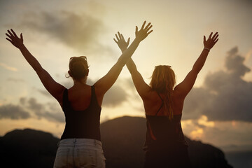 Travel, freedom and girl friends with hands up celebration in nature for journey, explore or adventure at sunset. Sunrise, trip and back or excited women outdoor for summer, break and bonding holiday