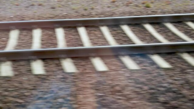 Close-up view of railway tracks on a gravel bed, illustrating themes related to travel, transportation, and infrastructure. the perspective focuses on the parallel metal rails and wooden ties, the eng