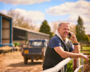 Mature Male Farm Worker Standing Outside Barn Making Call On Mobile Phone © Monkey Business