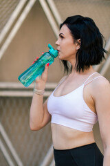 Workout, hydration and a sports woman drinking water outdoor in the city during running and fitness exercise. Hydrated with a female athlete training in an urban town for health. Sport concept. 