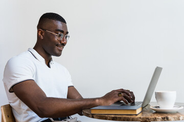 Smiling millennial african american casual man in glasses working with apps or communicating online...