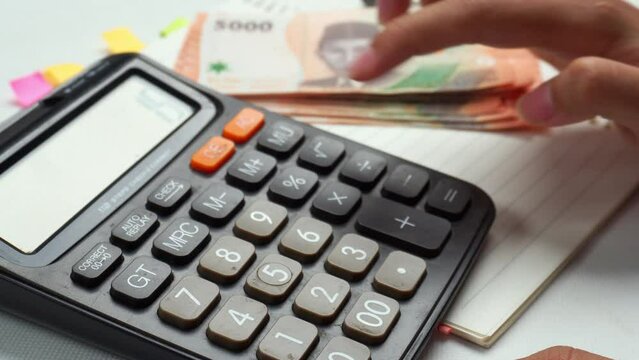 counting money indonesian rupiah with a calculator on table