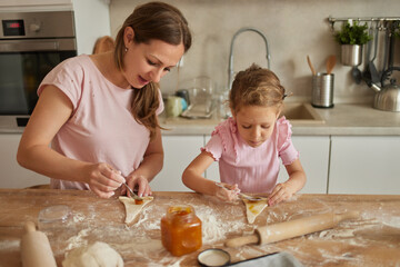 Mother and daughter baking homemade croissants in the kitchen