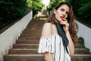 Gorgeous female with red lipstick in summer sleeveless clothes and black light scarf standing on...