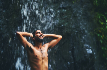 Fototapeta premium Man, waterfall and happy in nature on travel trip, eyes closed and freedom on adventure in sustainable environment. Bangladesh, outdoor and traveler on summer holiday, forest and journey or mountain