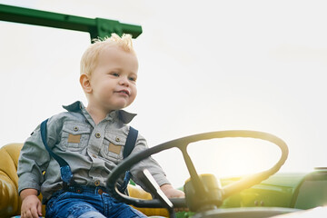 Funny, child and driving tractor on farm in countryside for learning agriculture outdoor in nature....