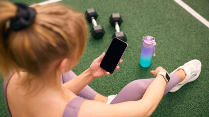 Overhead Shot Of Woman Exercising With Weights Checking Health Monitoring App On Mobile Phone