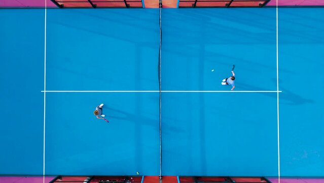 Top view of adult couple playing padel on outdoor court.
