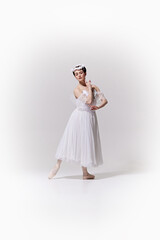 In classic white ballet costume, tender ballerina posing embodying grace and femininity against...