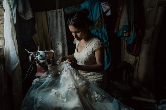 A woman is ironing a wedding dress. sewing white wedding dress. poor life