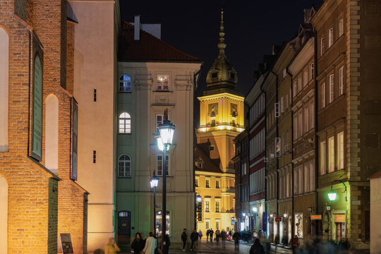 Low-rise buildings with passing crowd close to Castle Square (Plac Zamkowy), Swietojanska historical avenue at night, Old Town, Warsaw, Poland
