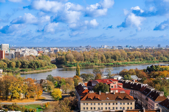Landscape panoramic view of city skyline with houses and skyscrapers under a blue sky with clouds and greenery around Vistula River with Praga borough visible, Warsaw, Poland