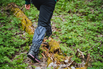 Fototapeta premium A hikers legs navigating mossy terrain in a forest on an outdoor adventure. Hiking, nature, outdoors, exploration, trekking, and footwear are some keywords related to the image