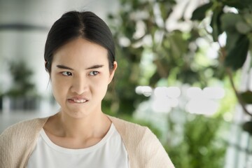 Angry upset young asian woman frowning, biting lips, expressing bad negative stressful facial...