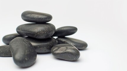 Spa hot stones arranged in a pile against a white backdrop