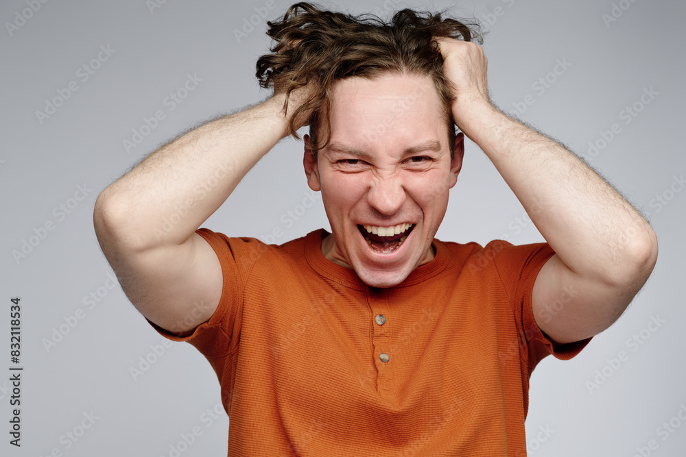 Canvas Prints medium closeup studio portrait of angry young caucasian man wearing orange t-shirt pulling his hair 