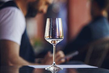 White wine glass at the table on summer terrace of restaurant background. Blind tasting concept. 