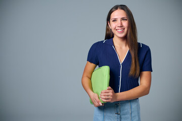 Studio Portrait Of Smiling Female College Or University Student With Laptop Bag On Grey Background