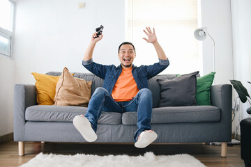 Full Length Photo Of Surprised Young Gamer Showing Happy Expression Win The Game While Sitting On...