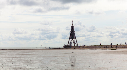 Panoramic photo of the lighthouse in Cuxhaven at low tide and bad weather. Thick dark clouds over...