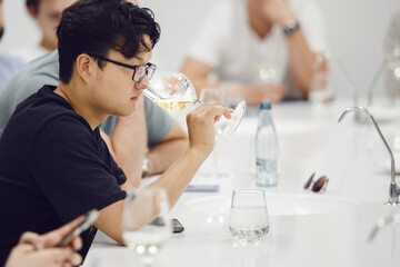 Asian ethnicity sommelier tasting white wine based smelling during study in wine school. Alcoholic...