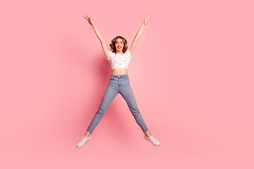 Full size photo of lovely young woman jump raise hands stretch legs dressed stylish white garment hairdo isolated on pink color background