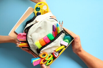 Back to school donation drive concept. Top view cardboard box with backpack full of colorful school...